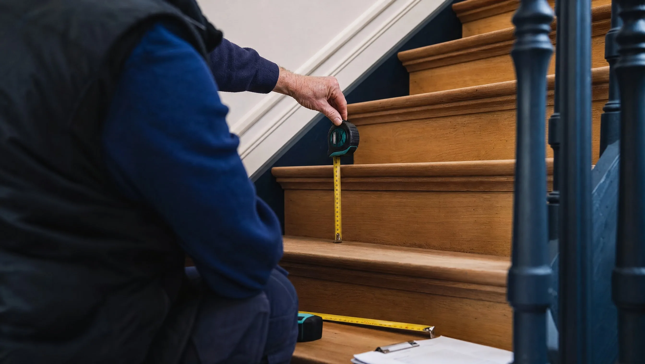 expert mesurant la hauteur de marche et le giron d'un escalier intérieur